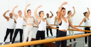 People practicing barre exercises during group fitness classes at a local gym
