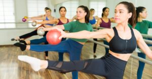 Women practicing barre with fitness balls during group fitness classes at top studios in New York City