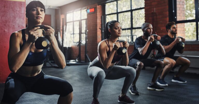 People doing kettlebell squats in group fitness classes in New York City